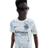 A young Black man in sunglasses wears an Inter Milan football jersey with a blue and teal geometric pattern, set against a solid white background.