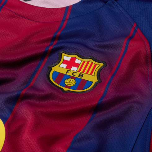 Close-up of an FC Barcelona club crest on a textured blue and burgundy soccer jersey.