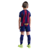 Back view of a boy in a blue and maroon FC Barcelona football kit and neon green cleats against a solid black background.