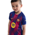 A young boy wearing an FC Barcelona soccer jersey with the Spotify logo, set against a black background.