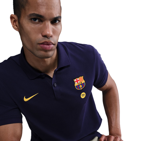 A man in a navy blue Nike FC Barcelona polo shirt featuring the club crest and yellow Spotify logo against a black background.