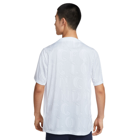 Rear view of a person wearing a white short-sleeved shirt with a subtle, all-over "CFC LONDON" typographic pattern.