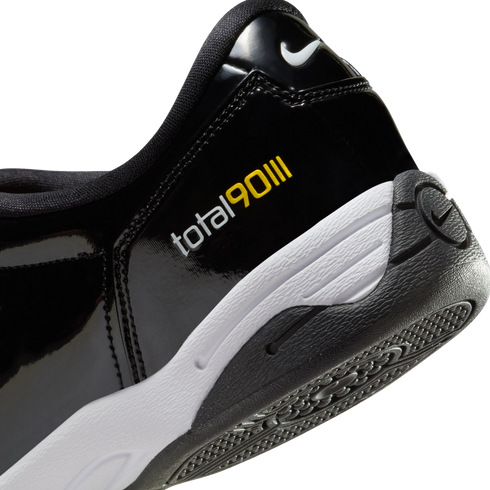 Close-up of the heel of a black patent leather Nike Total 90 III shoe with white and yellow branding, a white midsole, and a black textured outsole.