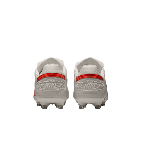 Rear view of two white soccer cleats with red heel accents and embossed "HIKE" branding against a black background.