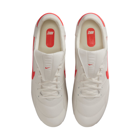 Top-down view of white Nike sneakers with bright red-orange accents and logos on a black background.