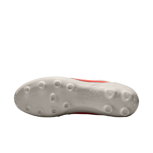 Underside of a white Nike soccer cleat showing circular studs and an ornate floral design on the sole, set against a solid black background.