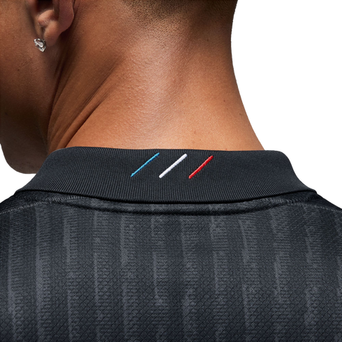 Close-up of the back of a person's neck wearing a charcoal grey shirt with three diagonal blue, white, and red stripes embroidered on the collar.