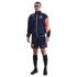 A man modeling a navy blue and orange Nike FC Barcelona track jacket and matching shorts against a solid black background.