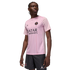 A man models a light pink Jordan Brand Paris Saint-Germain soccer jersey and matching black pinstripe shorts against a black background.