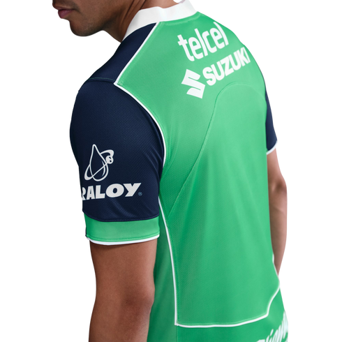 Back view of a man wearing a green sports jersey with navy blue sleeves, featuring white sponsor logos for Telcel, Suzuki, and Raloy.