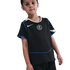 A young child wearing a black Nike Chelsea FC football kit with blue and white trim, standing against a solid black background.