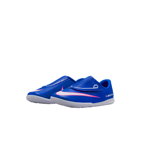 Blue Nike Mercurial indoor soccer shoes for toddlers with a white swoosh, pink trim, and hook-and-loop strap, shown on a black background.