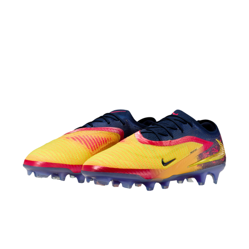 A pair of Nike soccer cleats with a yellow, orange, and navy blue gradient upper and purple soles, set against a solid black background.