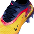 Close-up of a Nike soccer cleat featuring a navy blue knit upper, yellow and orange stripes, pink accents, and a textured gold Swoosh logo.