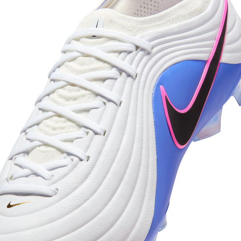 Close-up of a Nike soccer cleat with a white textured upper, blue side panel, and a black swoosh outlined in pink. Features white laces and a small gold swoosh.