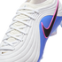 Close-up of a Nike soccer cleat with a white textured upper, blue side panel, and a black swoosh outlined in pink. Features white laces and a small gold swoosh.