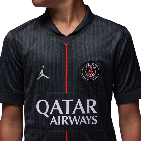 Close-up of a black Paris Saint-Germain jersey featuring the Jordan logo, PSG crest, and Qatar Airways sponsor text, with a thin red vertical line down the center.
