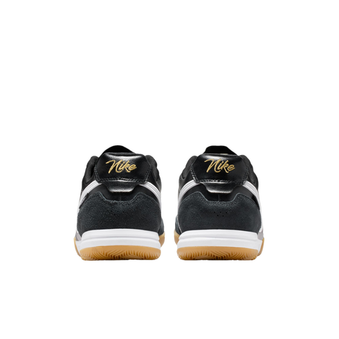 Rear view of two black Nike sneakers with gold script logos on the heels, white midsoles, and tan gum outsoles against a solid black background.
