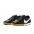 A pair of black Nike indoor soccer shoes with white swooshes and gum rubber outsoles, shown against a solid black background.