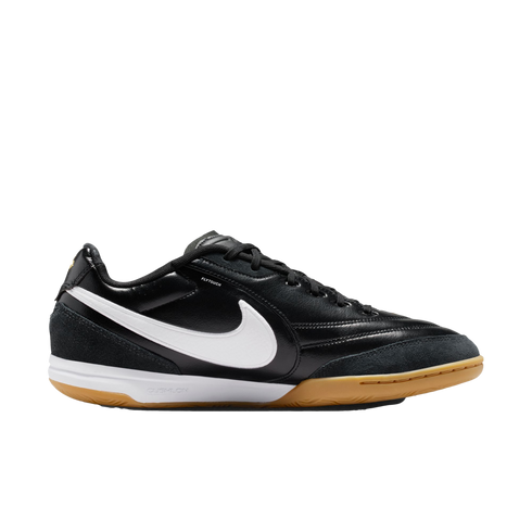 Profile view of a black Nike indoor soccer shoe with a white swoosh, white midsole, and gum outsole, set against a black background.
