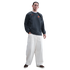 A man wearing a dark grey Inter Milan Nike sweatshirt and wide-leg off-white trousers against a black background.
