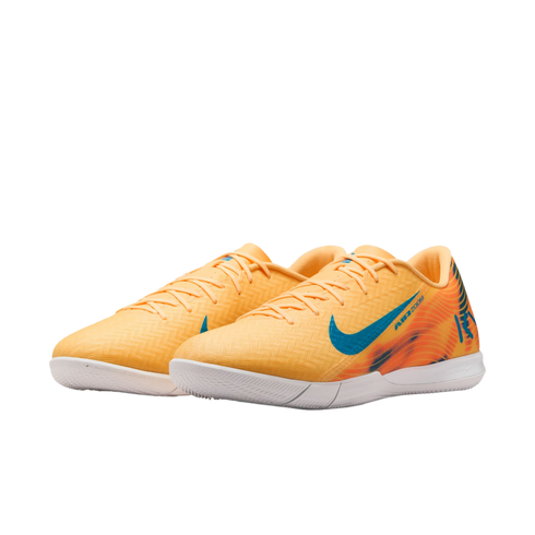 A pair of orange Nike Air Zoom indoor soccer shoes with teal swoosh logos and white outsoles, set against a black background.
