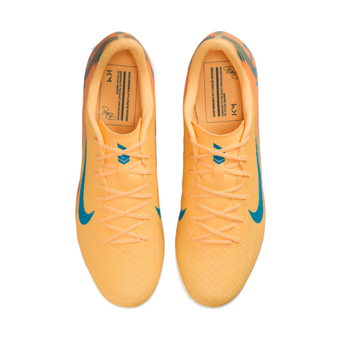 Top-down view of bright orange Nike soccer shoes with blue swooshes and Kylian Mbappé "KM" branding on the insoles.