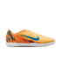 A Nike Mercurial indoor soccer shoe in light orange with blue accents and Kylian Mbappé "KM" branding on the heel, set against a black background.