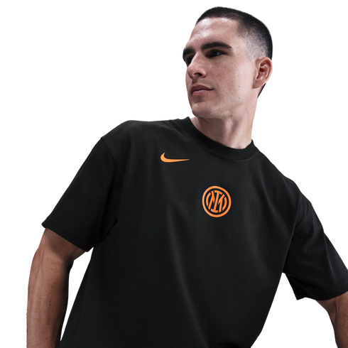A man wearing a black Inter Milan t-shirt with an orange Nike swoosh and club crest, looking to the side against a black background.