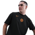 A man wearing a black Inter Milan t-shirt with an orange Nike swoosh and club crest, looking to the side against a black background.