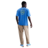 Back view of a man wearing a blue Nike t-shirt with a yellow "THFC" graphic, tan pants, and blue sneakers against a black background.