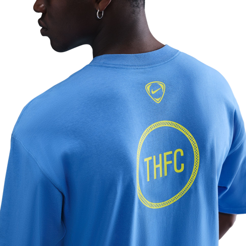 Back view of a person in a light blue t-shirt featuring a small yellow Nike logo and a larger yellow circular "THFC" graphic.
