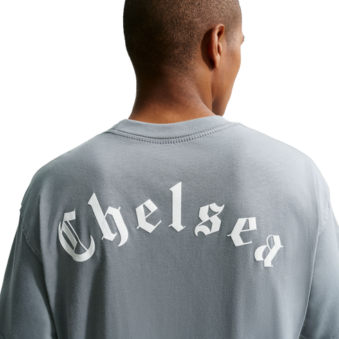 Back view of a person wearing a gray t-shirt with "Chelsea" printed in white Old English lettering across the back, set against a solid black background.
