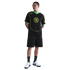 A man poses in a black Nike T90 soccer jersey, black cargo shorts, and white sneakers against a white background.