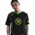 A man with arm tattoos wears a black Nike Total 90 jersey with neon green and yellow accents, set against a plain white background.
