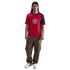 Man with long dark hair wearing a red Nike Total 90 jersey, olive green cargo pants, and white sneakers.