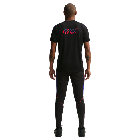 Back view of a man wearing a black t-shirt with a red and blue "U.S." script and matching black athletic pants against a black background.