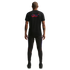 Back view of a man wearing a black t-shirt with a red and blue "U.S." script and matching black athletic pants against a black background.