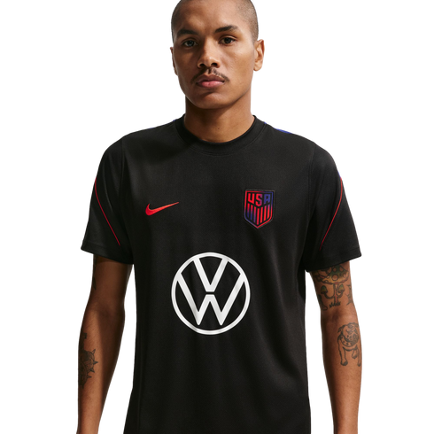 A man in a black US Soccer training jersey featuring a red Nike swoosh, the team crest, and a large white Volkswagen logo in the center.