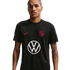 A man in a black US Soccer training jersey featuring a red Nike swoosh, the team crest, and a large white Volkswagen logo in the center.