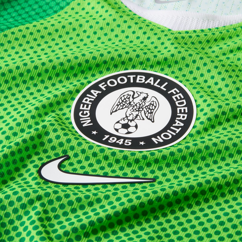 Close-up of a green Nike Nigeria football jersey with dark green polka dots, featuring the Nigeria Football Federation crest and a white swoosh logo.
