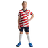 A young girl in a red and white wavy striped USA soccer uniform, navy shorts, and bright blue cleats, standing against a solid black background.