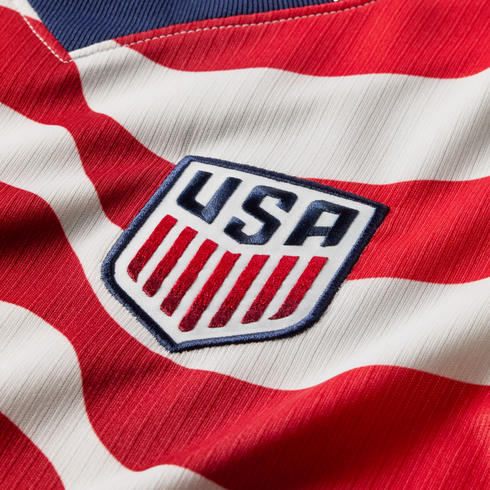 Close-up of the U.S. Soccer national team crest embroidered on a red and white striped jersey.