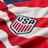 Close-up of the U.S. Soccer national team crest embroidered on a red and white striped jersey.
