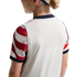 Rear view of a person wearing a white athletic jersey with red and white striped sleeves and navy blue trim.