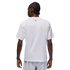 A rear view of a man with braided hair wearing a white t-shirt with a small black logo on the back, set against a black background.