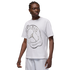 A person with braided hair wears a white T-shirt featuring a silver Jordan x PSG graphic, paired with white shorts against a solid black background.