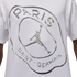 White t-shirt with a large, liquid-metal style silver graphic featuring "PARIS SAINT-GERMAIN" text surrounding the iconic Jordan Jumpman logo.