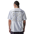 A person with braided hair and tattoos stands with their back to the camera, wearing a silver jersey with "JORDAN 23" printed on the back against a black background.