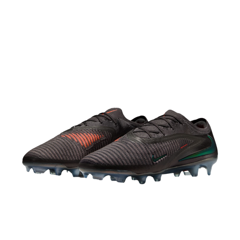 A pair of black Nike soccer cleats with orange accents and iridescent green swooshes against a black background.